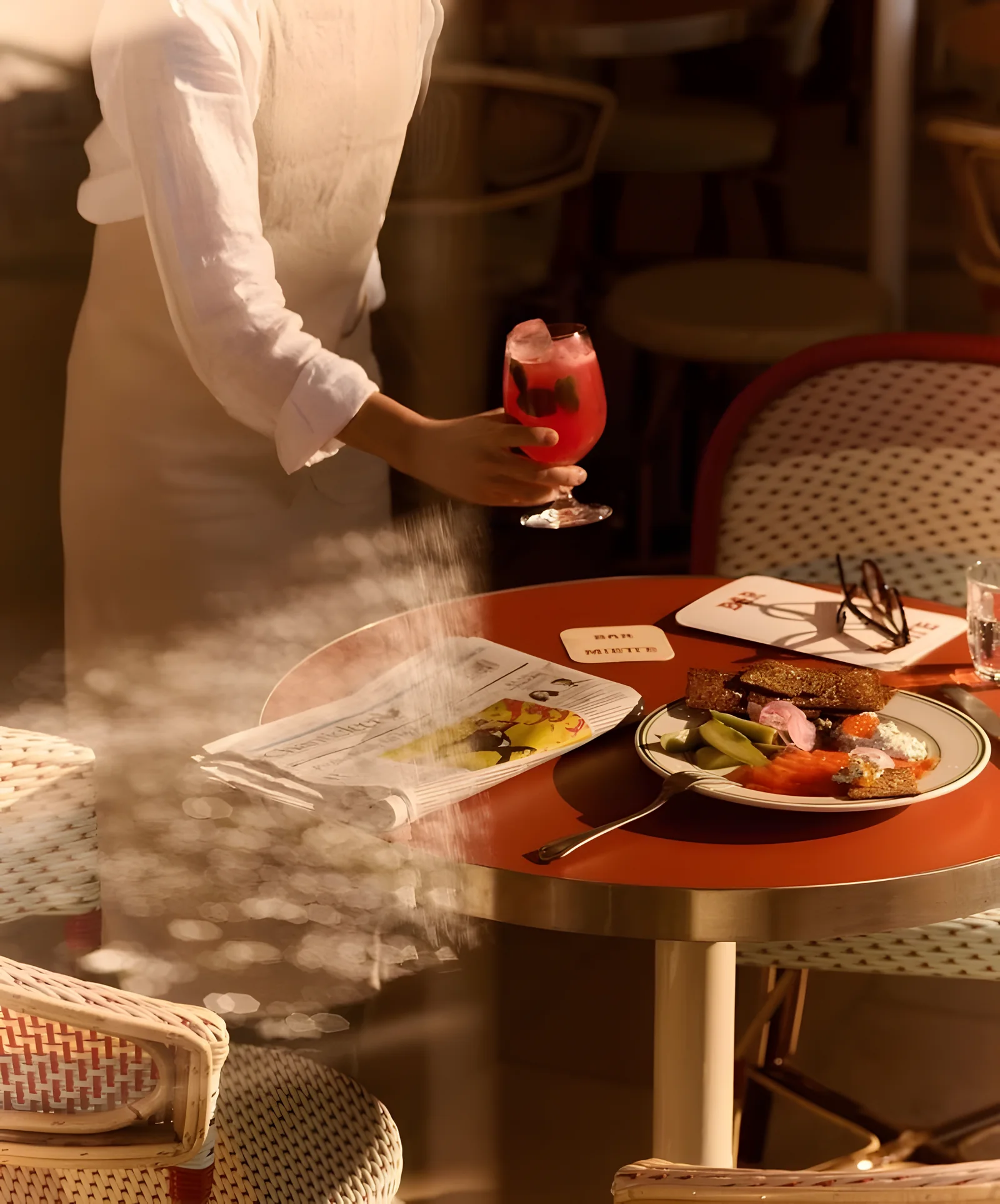 Un serveur dépose un verre sur une table en terrasse